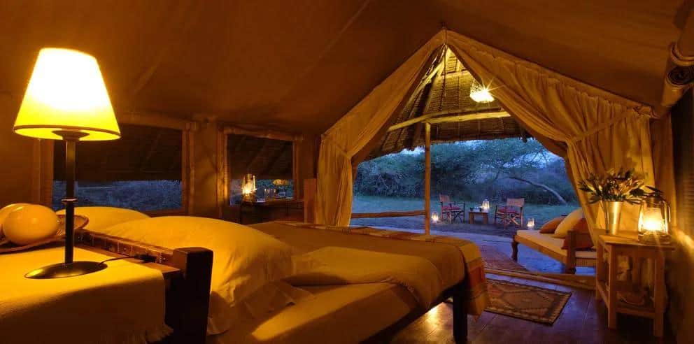 Luxury safari tent interior with twin beds and ambient lighting overlooking the bush in Kenya’s Masai Mara