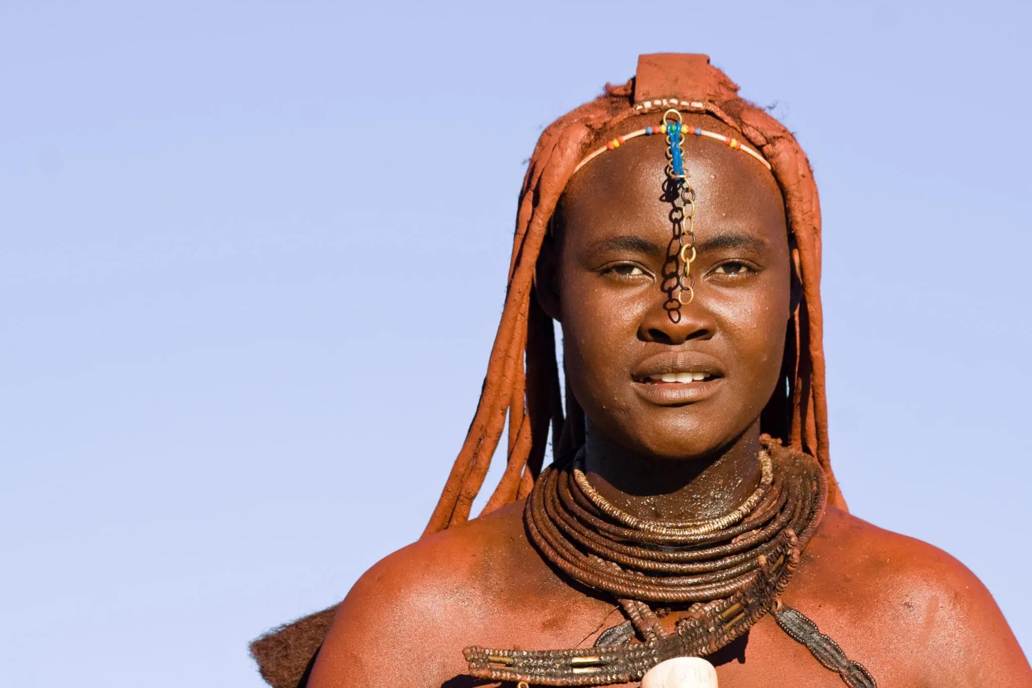 Portrait of a Himba woman with traditional red ochre hairstyle and ornate jewelry in Namibia, Africa.